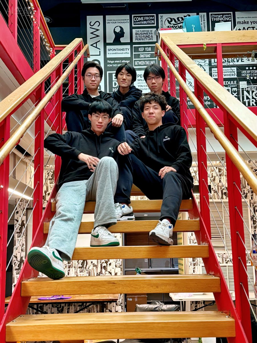 Jimmy with his hackathon team, sitting on red stairs