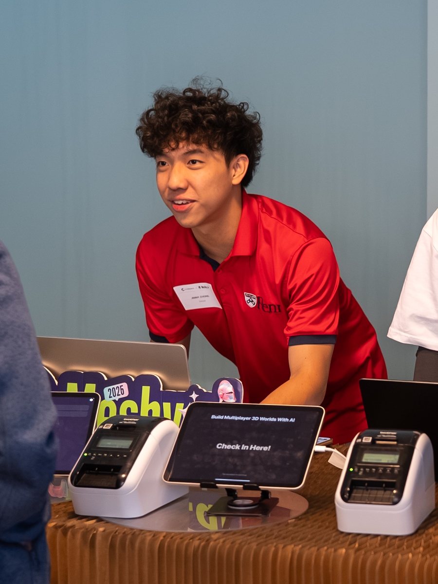 Jimmy in a red Penn polo greeting a guest at the check-in desk of an SF Tech Week event